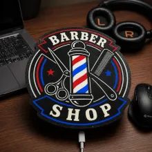 Lightbox iluminado con el logotipo de una barbería sobre un escritorio.